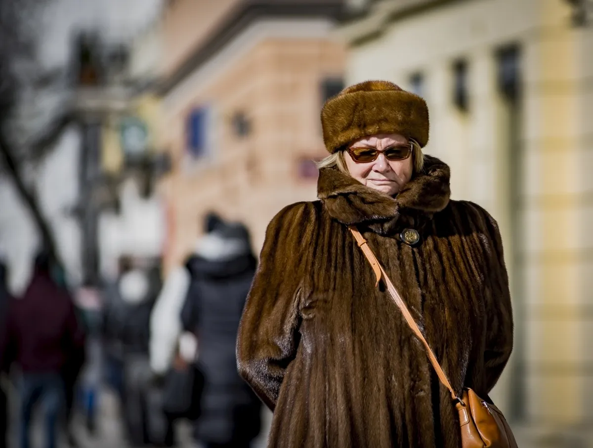 Older woman in a brown fur coat and hat on a city street